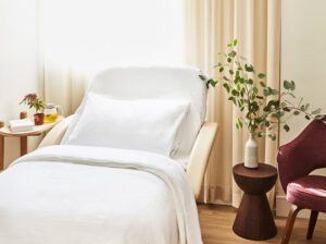 A spa-inspired patient room with a bed, side tables, plants, and a chair